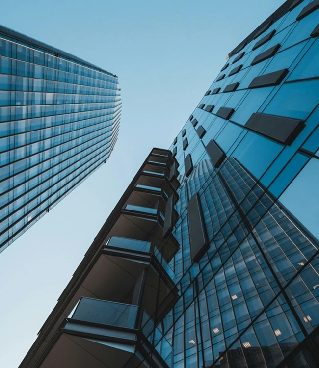 Low angle view of modern blue glass skyscrapers representing the Technolease corporate infrastructure backing Smarter Living security rentals.